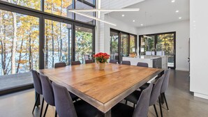 Un espace repas moderne avec une grande table en bois, entourée de chaises, et un vase rempli de fleurs rouges.