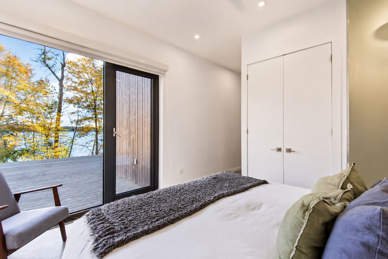 Una camera da letto con un letto, una sedia, un'ampia finestra e un armadio.