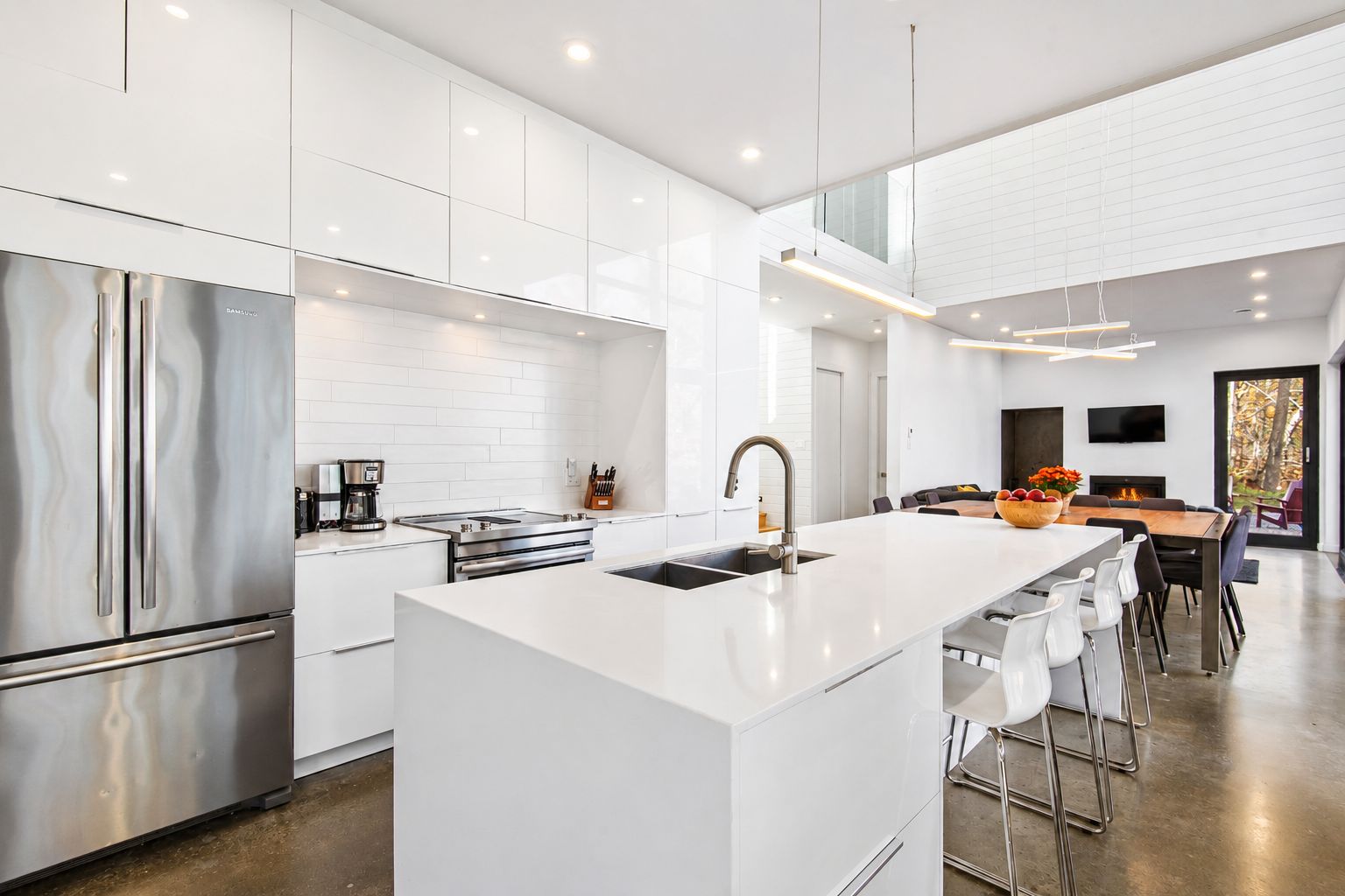 A modern kitchen with a central island, stainless steel appliances, and a dining area with a large table and chairs.