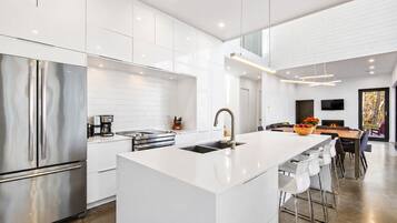 A modern kitchen with a central island, stainless steel appliances, and a dining area with a large table and chairs.
