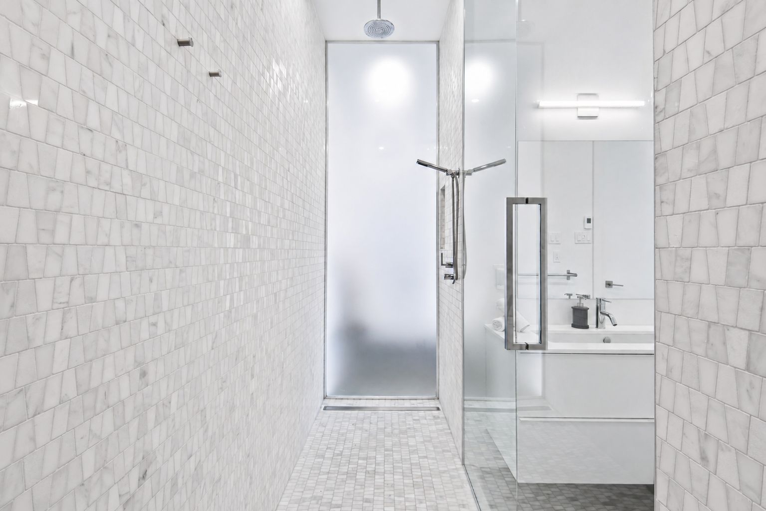 A modern bathroom with a glass shower enclosure, a mirror, and a sink.