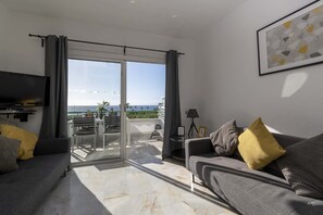 Relax in this stylish living room with a sofa, flat-screen TV, and balcony access.