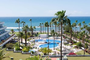 Relax by the pool surrounded by palm trees and lounge areas, with access to the beach and ocean views.