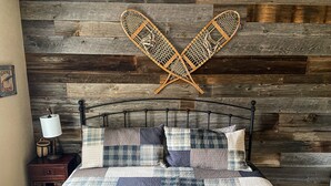 A bed with a patchwork quilt, a wooden headboard, and a wall-mounted rack. - Charming home with direct lake access, close to town (Greenville)