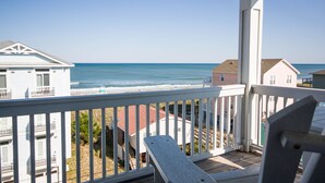 Een balkon met uitzicht op de oceaan en omliggende huizen.