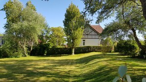 Ein gepflegter Rasen mit einem traditionellen Haus im Hintergrund.