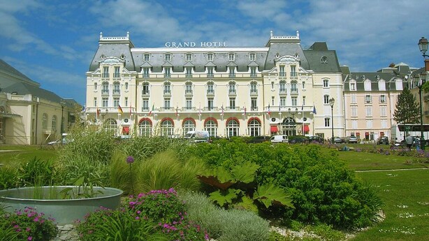 Un grand bâtiment historique portant l’inscription « Grand Hôtel », doté d’une façade symétrique, de nombreuses fenêtres et d’une entrée centrale.