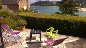Une terrasse avec une table et quatre chaises, offrant une vue sur la côte.