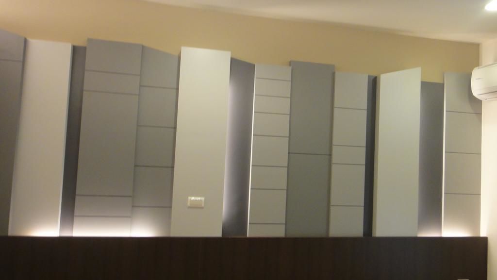 Une chambre d’hôtel moderne dotée d’une grande tête de lit de couleur claire et d’un élément décoratif en bois foncé.