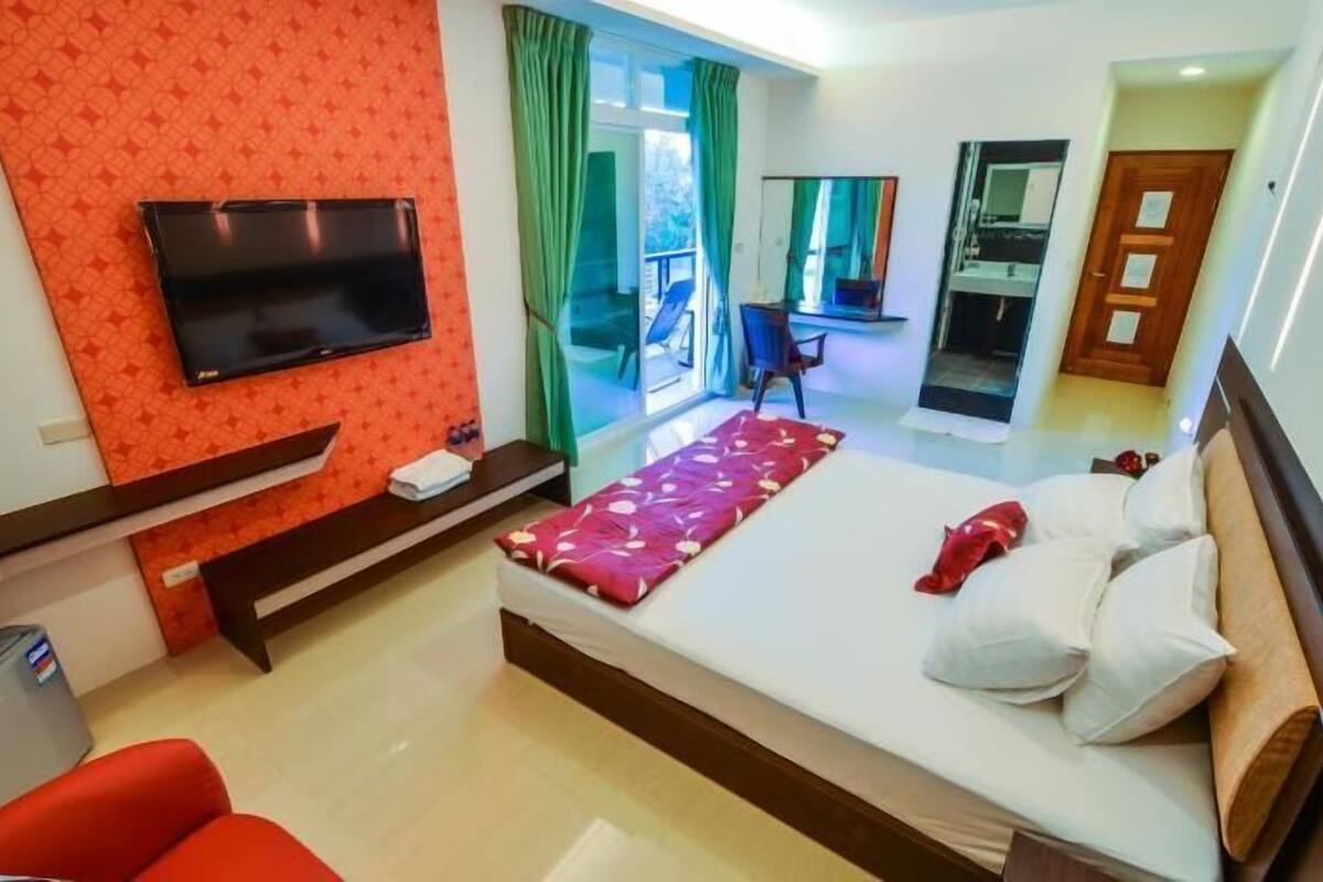Una habitación de hotel con cama, televisor, escritorio y una silla.