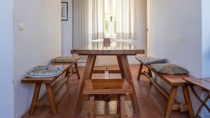 A dining area with a wooden table and benches, a window with curtains, and a radiator on the wall. - The sea in a room (Lerici SP)