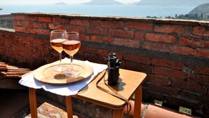 A table with two glasses of wine, a camera, and a view of the sea and mountains. - The sea in a room (Lerici SP)