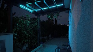 Un espace extérieur aménagé en terrasse, doté d’une pergola et de guirlandes lumineuses.