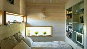 Ein Schlafzimmer mit Bett, Fenster und Bücherregal.