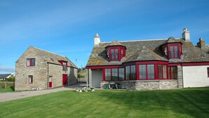 A stone house with red doors and windows, a stone exterior, and a well-maintained lawn. - Luxury Self Catering Lodge & Barn - Along NC500 - Indoor Private Swimming Pool (Latheronwheel)