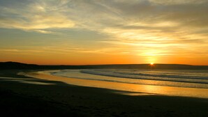 A beach at sunset with the sun setting over the horizon. - Luxury Self Catering Lodge & Barn - Along NC500 - Indoor Private Swimming Pool (Latheronwheel)