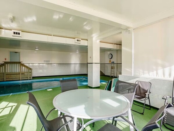 A pool area with a round table and chairs, a wooden deck, and a small staircase.