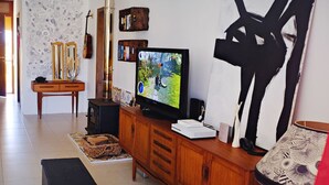 A living room with a television, wooden cabinet, and a large abstract painting. - Large seaside penthouse, with breathtaking country views (Iż-Żebbuġ)