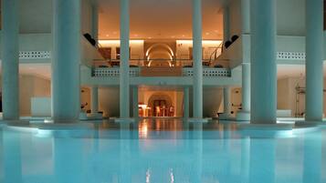 Amplia zona de piscina interior con una zona de estar central y varios niveles de balcones.