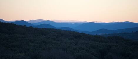 A mountainous landscape with a forested foreground and a series of hills in the background.