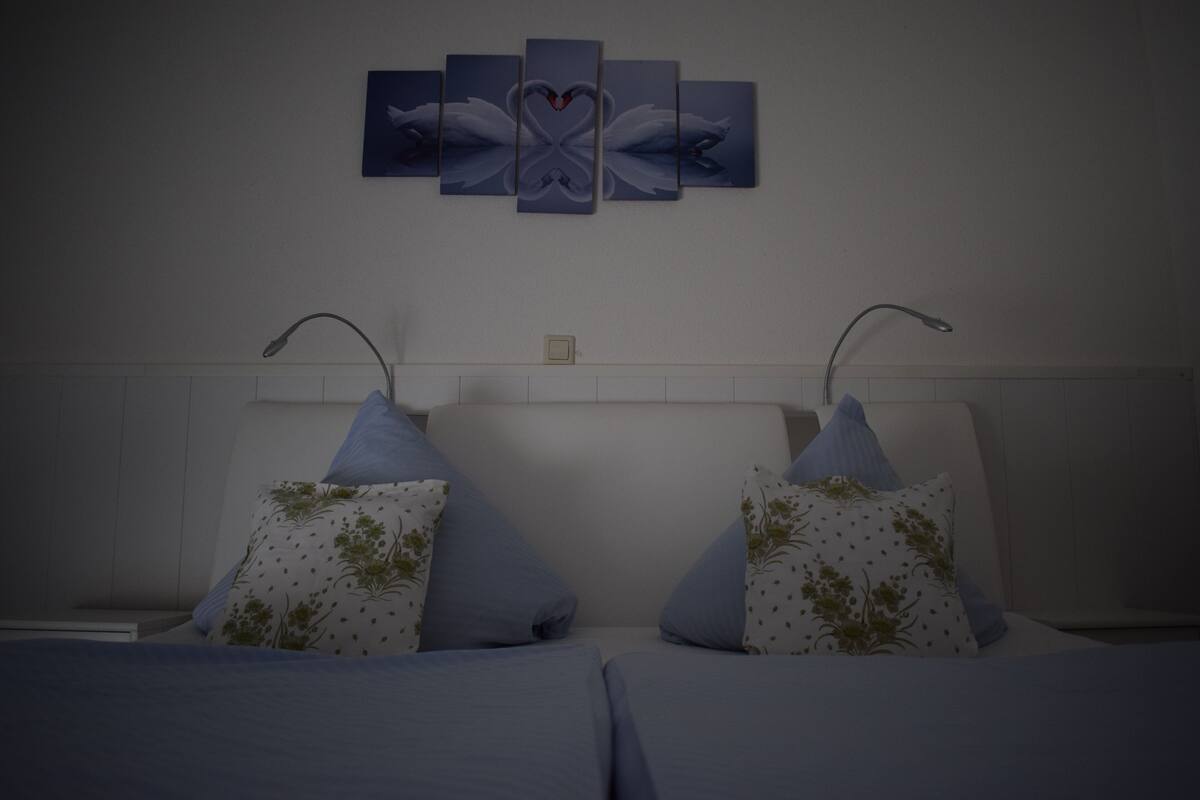 Une chambre à coucher avec un lit, des oreillers et une œuvre d’art accrochée au mur.
