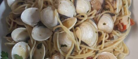 A plate of pasta with clams and a garnish of parsley.