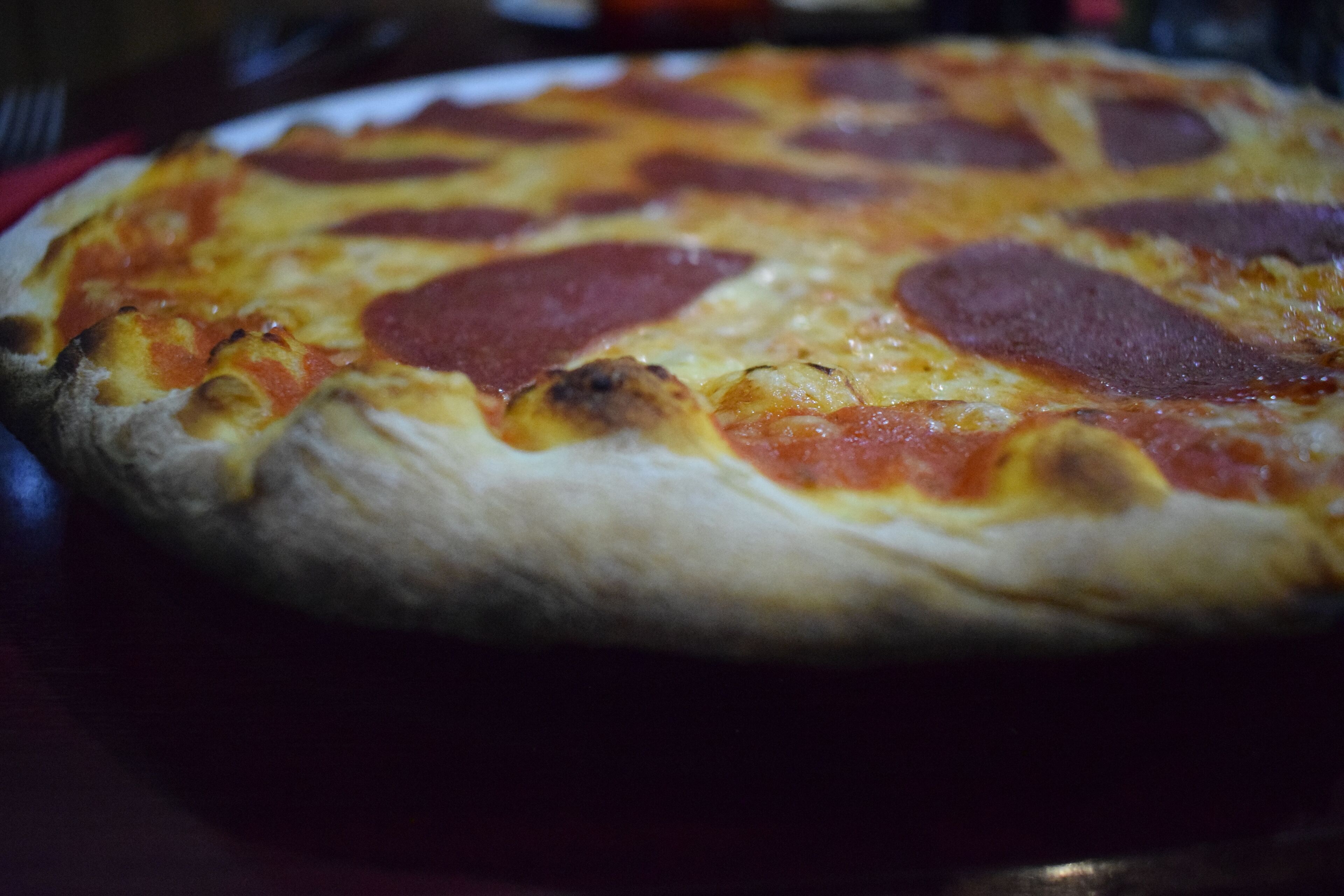 A pizza with pepperoni slices on a white plate.
