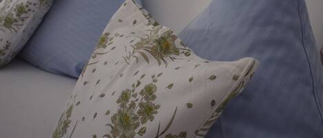 Ein weißes Sofa mit blau-blumigen Kissen.