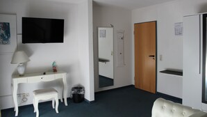 A hotel room with a desk, chair, television, and a mirror. - Zum Goldenen Wagen (Maulburg)