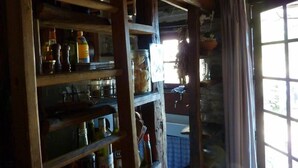 Un interior rústico con estantes de madera que sostienen diversos utensilios de cocina y una ventana con cortinas.