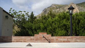 Un mur de pierre avec une rambarde en métal, un lampadaire et une montagne en arrière-plan.