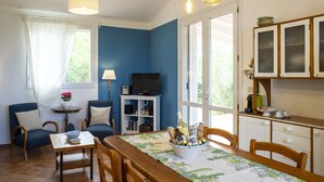 Une pièce comprenant une table à manger, des chaises, un téléviseur et un meuble avec des portes en verre.