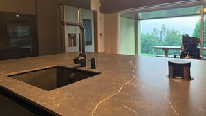 Una cocina moderna con encimera de mármol, un lavamanos y un horno empotrado.