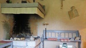 A cozy room with a stone fireplace, a bed with a headboard, a table with a tray, and a lamp. - Holiday Home Augusta (Zminj)