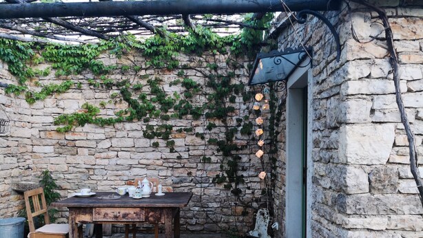 A rustic outdoor seating area with a stone wall, a wooden table, and chairs. - Holiday Home Augusta (Zminj)