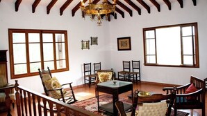 A room with a high ceiling, wooden beams, a chandelier, multiple windows, and a central table with chairs. - Bella Vista.
ETV /1070 BELLA VISTA. (Sóller ,Biniaraix .)