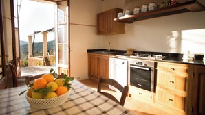 A kitchen with wooden cabinets, a black countertop, and a bowl of fruit on the table. - Bella Vista.
ETV /1070 BELLA VISTA. (Sóller ,Biniaraix .)