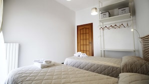 Ein Hotelzimmer mit zwei Betten, einem Kleiderschrank mit Kleiderbügeln und einer Tür.