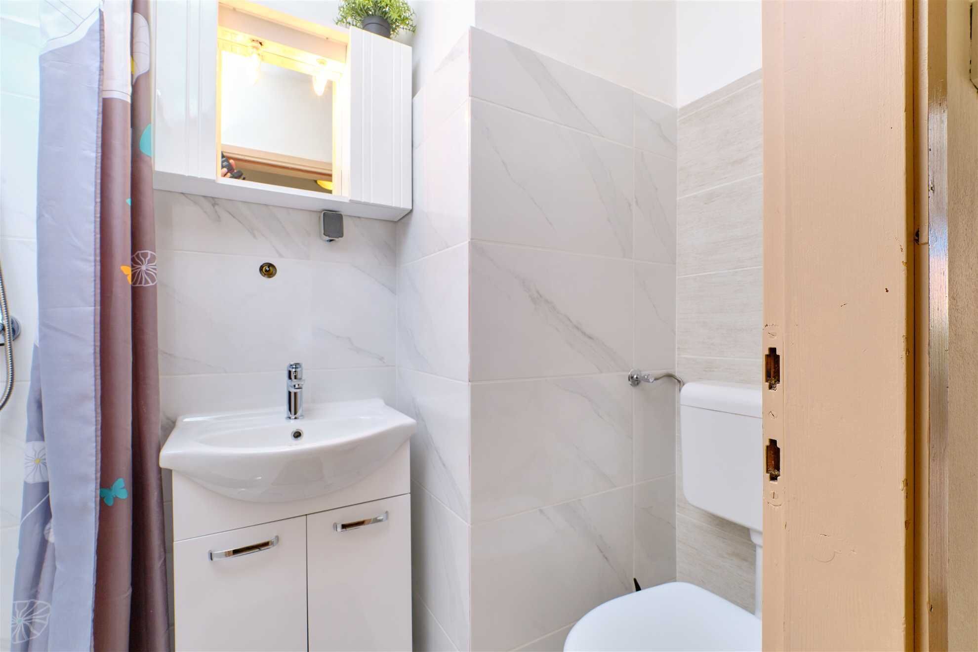 Une salle de bain avec un lavabo blanc, un miroir au-dessus et des toilettes.