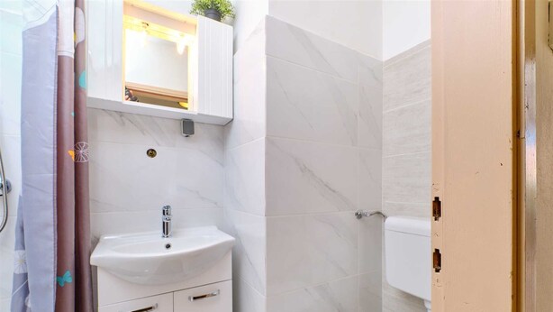 A bathroom with a white sink, a mirror above it, and a toilet.