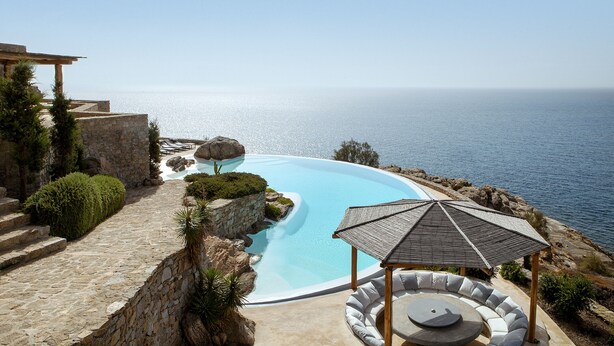 Ein Pool mit Meerblick, Steinstufen und eine Sitzecke mit einer Pergola.