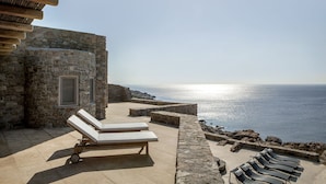 Ein Steinhäuschen mit einer Terrasse mit Blick auf das Meer, ausgestattet mit Liegestühlen und Meerblick.