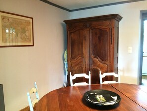 Een eetkamer met een houten tafel, witte stoelen en een grote houten kast.