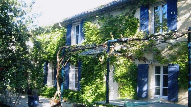 Un bâtiment doté d’un mur en pierre et d’une treille recouverte de plantes grimpantes.