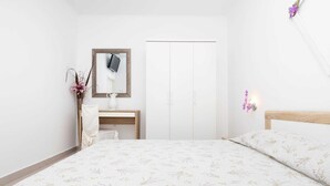 A bedroom with a bed, a bedside table, a mirror, a wardrobe, and a wall-mounted light fixture.
