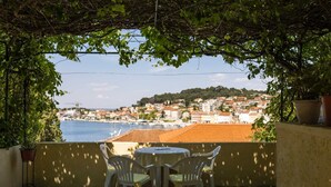 An outdoor patio with a table and chairs, overlooking a coastal town with buildings and boats.