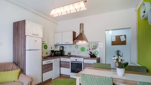 Une cuisine compacte équipée d’un réfrigérateur, d’un four à micro-ondes, d’une cuisinière et d’un évier. Un coin repas avec une table et des chaises est également disponible.