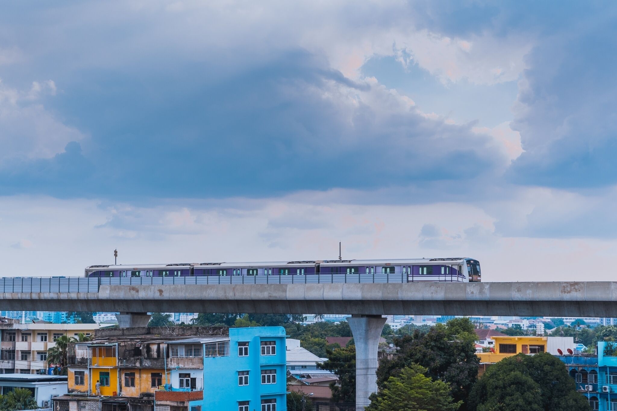 A train on an elevated track with colorful buildings in the background.