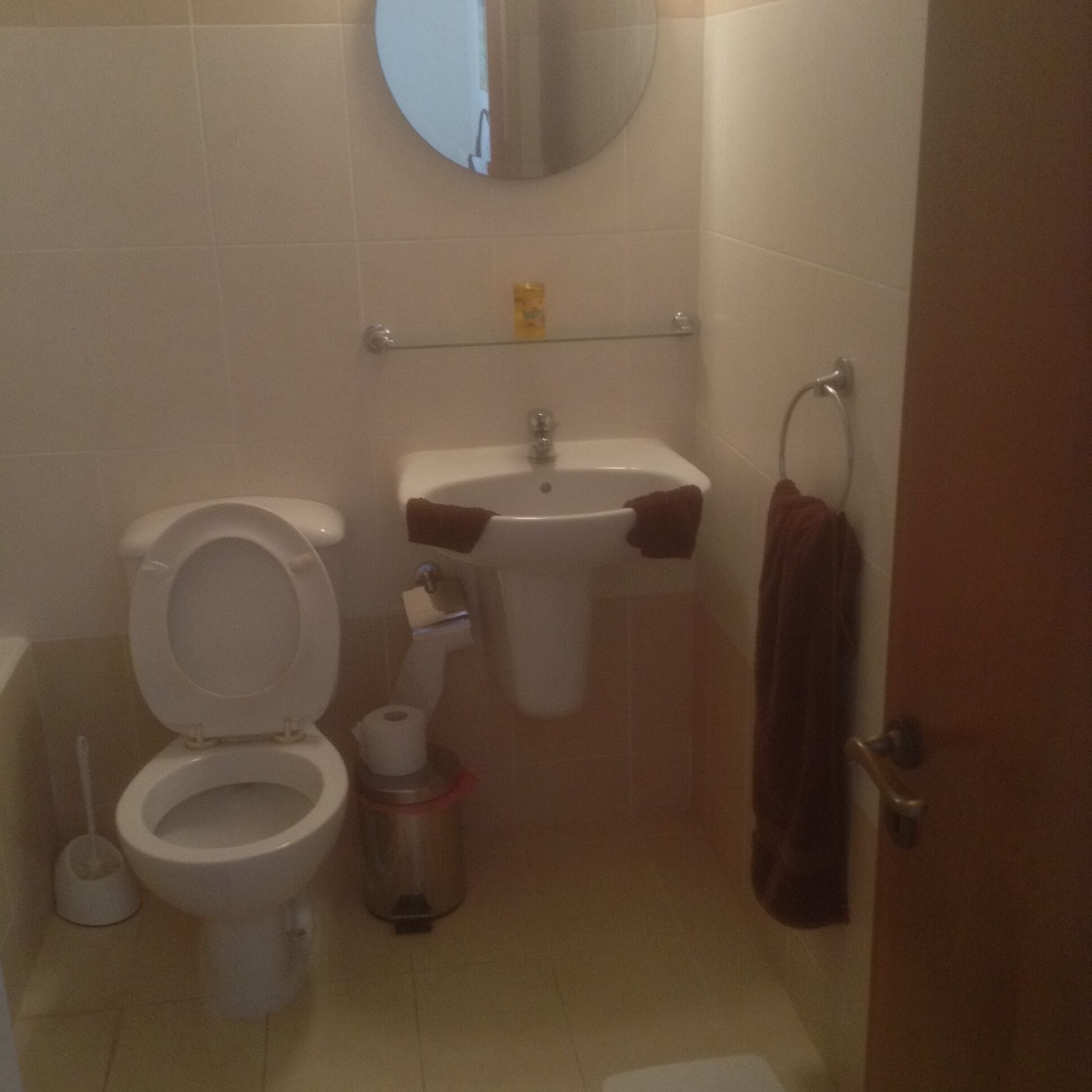 Et badeværelse med toilet, vask og spejl.