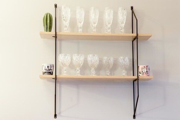 Een wandplank met twee rijen glazen vazen en een kleine potplant.
